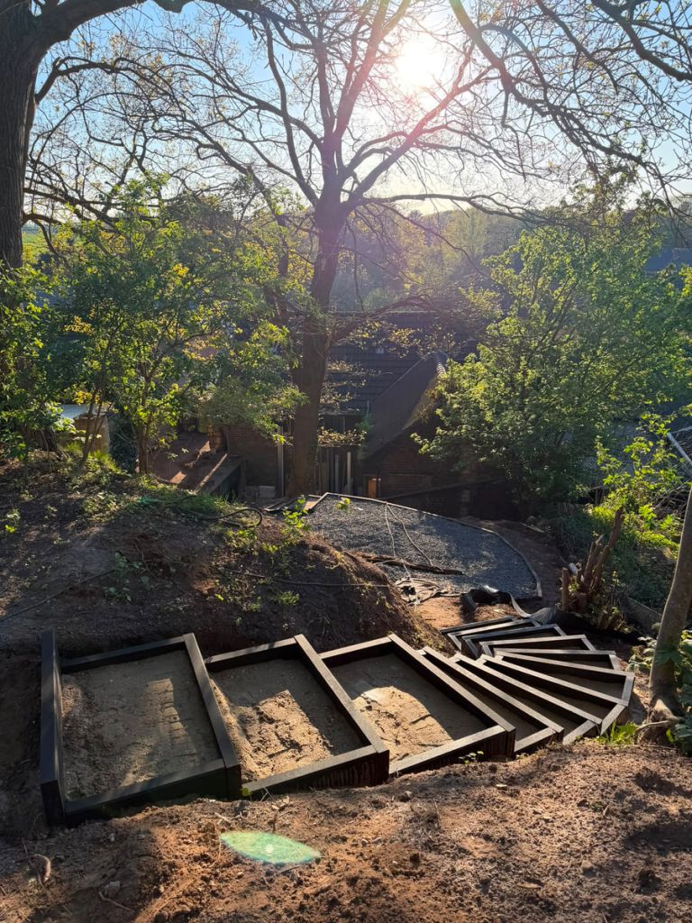Baustelle im Garten mit abgetragenem Hang und den ausgerichteten Rahmen einer neuen Gartentreppe
